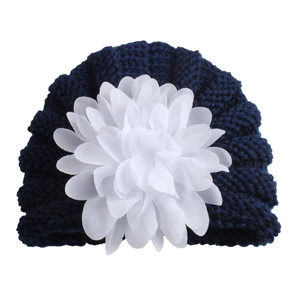 Bonnet en tricot bleu marine pour bébé orné d'une grande fleur blanche décorative