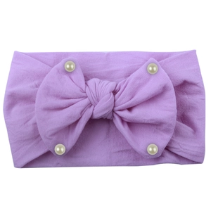 Detail of soft nylon lavender baby headband featuring a large bow and pearl accents