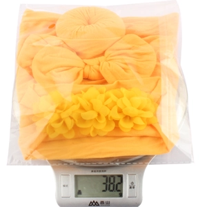 Detail view of a yellow soft nylon baby headband set on a digital scale weighing 38.2 grams