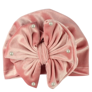 Detailed view of pink velvet baby hat featuring a large bow and white faux pearls