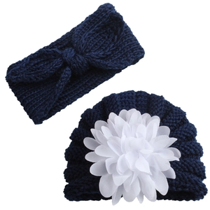 Detail of navy knit baby hat with white floral applique and matching bow headband set