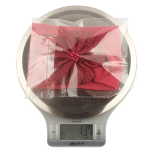 Détail d'un bandeau bébé en nylon rouge foncé avec fleur pesé sur une balance de cuisine