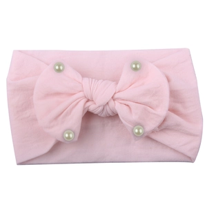 Detailed close-up of soft pink nylon baby headband with faux pearls and bow
