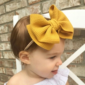 Detail of baby yellow nylon headband with a large textured waffle bow on a young child