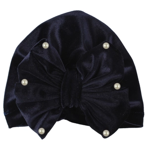 Detail of navy blue velvet baby turban hat with oversized bow and white pearl accents