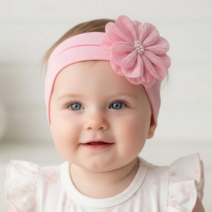 Détail d'un bandeau pour bébé en nylon rose avec une grande fleur et des perles douces