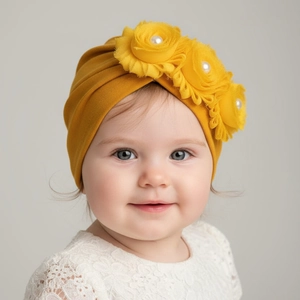 Dettaglio del turbante neonato giallo senape con tre fiori decorativi e perle