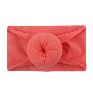 Détail d'un bandeau bébé rose corail avec un nœud donut en tricot doux élastique