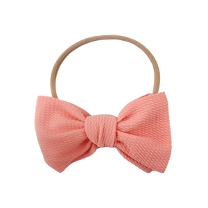 Detailed macro of salmon pink waffle knit bow headband with stretchy elastic band