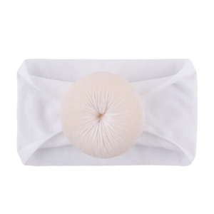 Détail d'un bandeau en nylon pour bébé avec côtes douces et ornement pompon beige délicat