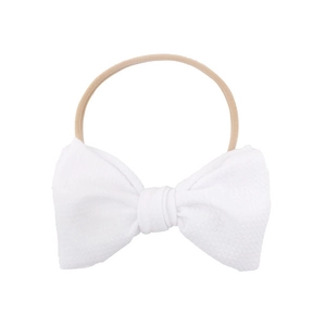 Detail of white waffle fabric bow on a soft nude nylon headband for infants and newborns