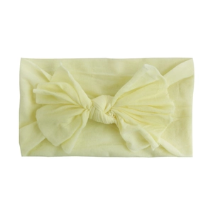 Close-up of soft nylon infant headband featuring a large pale yellow bow detail