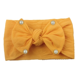 Elastic baby headband with a large yellow bow and white faux pearls in soft knit fabric