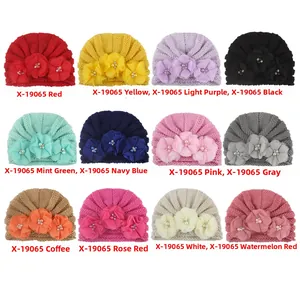 Collage of knit baby turban hats in twelve colors featuring 3D floral and pearl accents