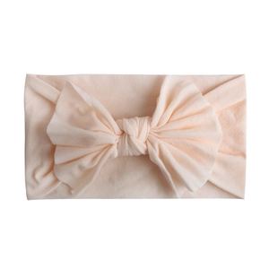 Close-up of soft elastic nylon baby headband with a large pale pink bow detail