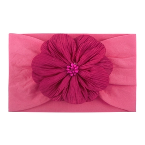 Détail d'un bandeau en nylon pour bébé avec fleur en tissu rose foncé et perles