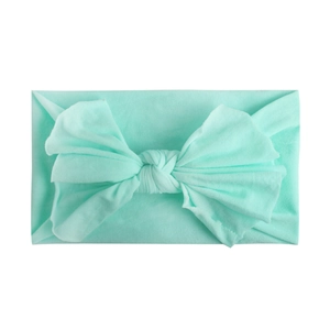 Detail of soft mint green nylon baby headband with large elastic bow decoration