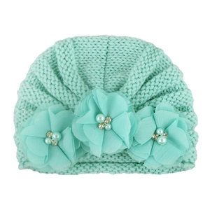 Detail of light green baby knitted hat featuring chiffon flowers with pearls and rhinestones