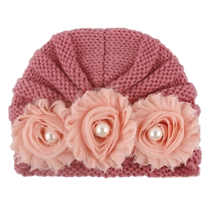 Dusty pink knitted baby beanie hat with decorative fabric flowers and pearl accents
