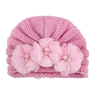 Close-up of pink knit baby hat with handmade chiffon flowers, pearls and rhinestones