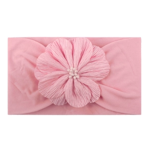 Vue détaillée du bandeau rose pour bébé avec fleur en tissu doux et centre en perle