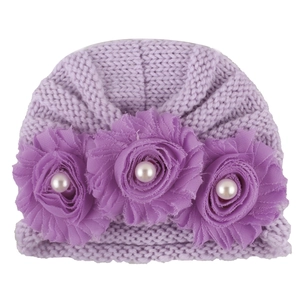 Detailed texture of purple knitted baby hat with chiffon flowers and white faux pearls