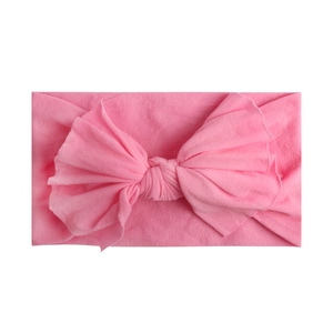 Detail shot of a soft pink nylon baby headband with a single layer knit bow texture