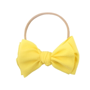 Vibrant yellow baby bow headband with honeycomb texture and nude nylon elastic band