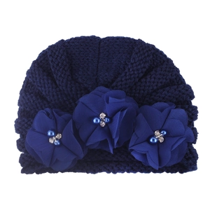 Detail of navy knit baby beanie featuring three chiffon flowers with pearls and rhinestones