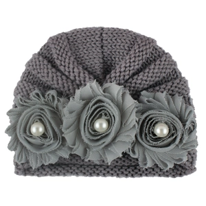 Detail of grey knitted baby turban hat with delicate fabric flowers and pearl accents