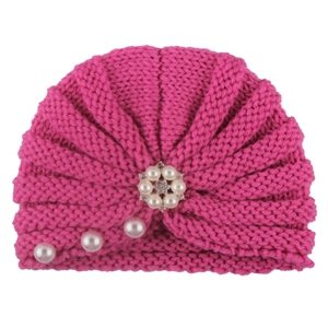 Detail of rose pink knitted baby turban hat with elegant pearl and rhinestone flower