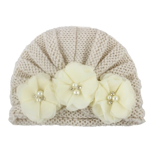 Detailed view of beige knit baby turban hat with three large silk flowers and pearls