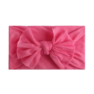 Close-up of pink soft nylon headband featuring a large handmade knot bow for infants