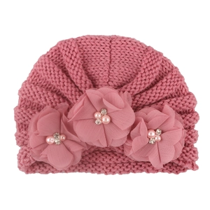 Pink knit baby beanie with ribbed texture and three chiffon flower accents with pearls
