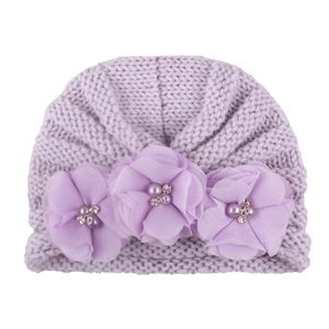 Detailed texture of lavender knitted baby hat with chiffon flowers, pearls, and rhinestones
