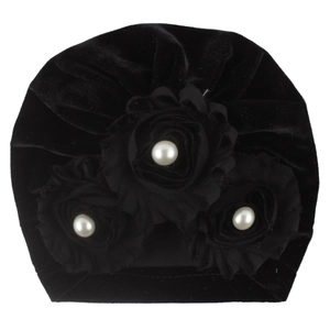 Detail of black velvet baby turban hat with three fabric flowers and white pearl centers