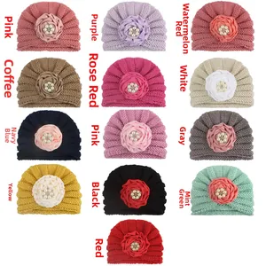 Vue à plat de treize turbans tricotés pour bébé avec fleurs et détails en perles