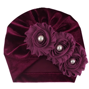 Detail view of burgundy velvet baby turban featuring handmade fabric roses and pearl accents