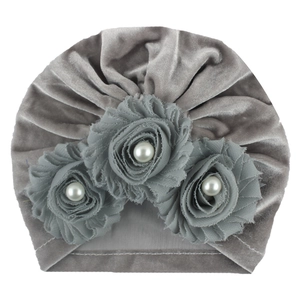 Macro detail of a grey velvet baby turban with three fabric roses and central pearls