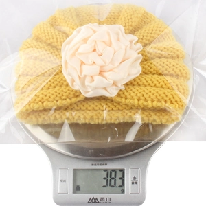 Detailed weight measurement showing 38.3g for the yellow flower baby knit beanie