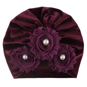 Close-up of burgundy velvet baby turban hat with three fabric flowers and white pearls
