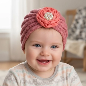 Détail d'un turban tricoté rose pour bébé avec grande rose en satin, perles et strass brillants