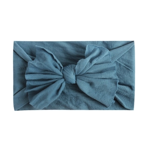 Detailed close-up of soft nylon teal headband with oversized bow and ribbed knit texture