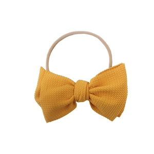 Ginger yellow waffle texture bow headband for infants on a nude elastic nylon band