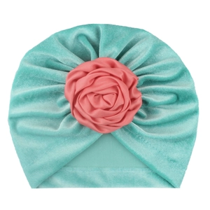 Détail du turban bébé en velours vert menthe avec une fleur décorative en satin rose