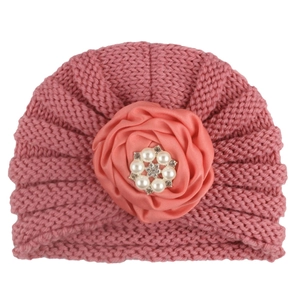 Texture de tricot détaillée du bonnet rose pour bébé avec grande rose en satin et perles