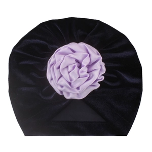Vue détaillée du bonnet turban en velours pour bébé avec une grande rose en satin violet