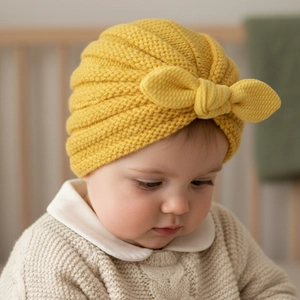 Detail of ginger yellow baby turban hat featuring textured knit and a large bow