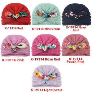 Detail view of seven colorful knit baby turbans with floral print bow decorations