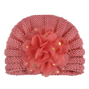 Detailed close-up of a pink baby turban hat featuring a large gold-dotted tulle flower